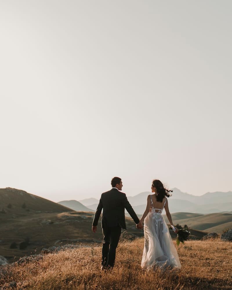 Gün batımında tepelerde yürüyen gelin ile damat